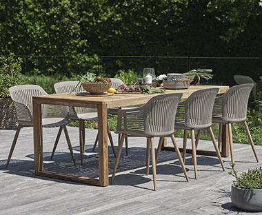 Gartentisch aus Holz und Schalenstühle in Beige auf einer Terrasse