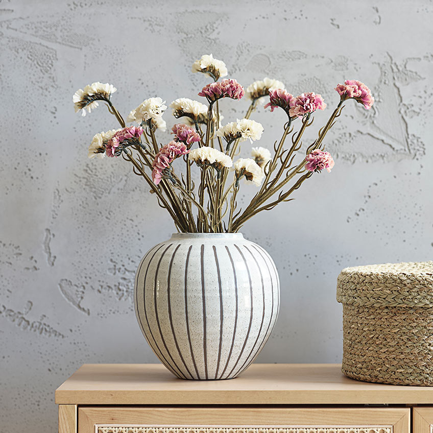 Schöne Vase auf einer Anrichte mit Kunstblumen in Weiß und Rosa