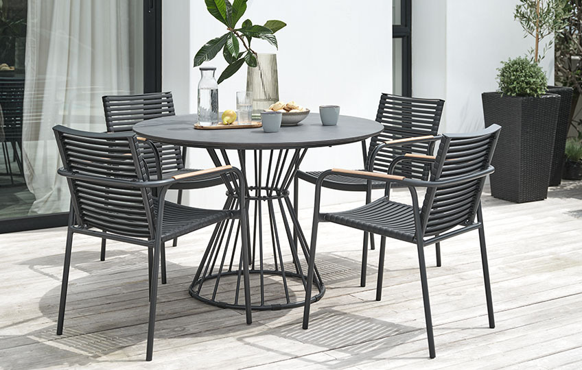 Runder Gartentisch mit einer Tischplatte aus Faserzement und Gartenstühle in Schwarz