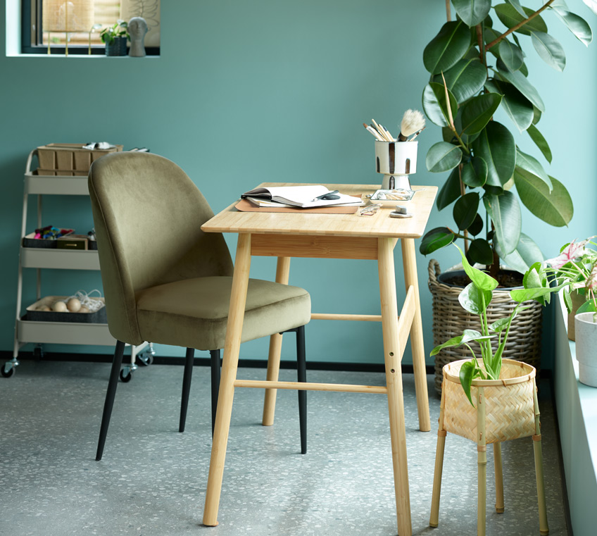 Schreibtisch aus Bambus und ein grüner Stuhl aus Samt 
